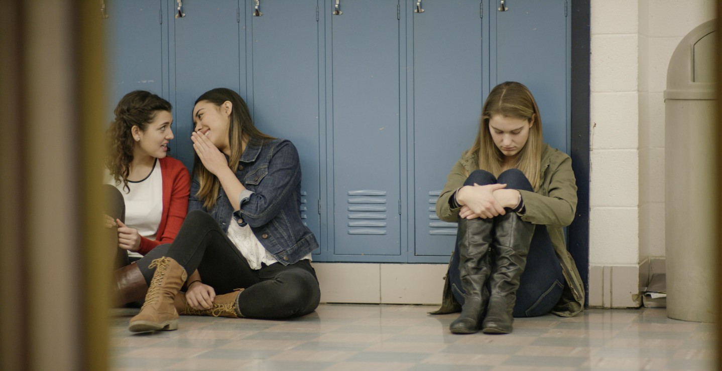 girls whispering at a locker||