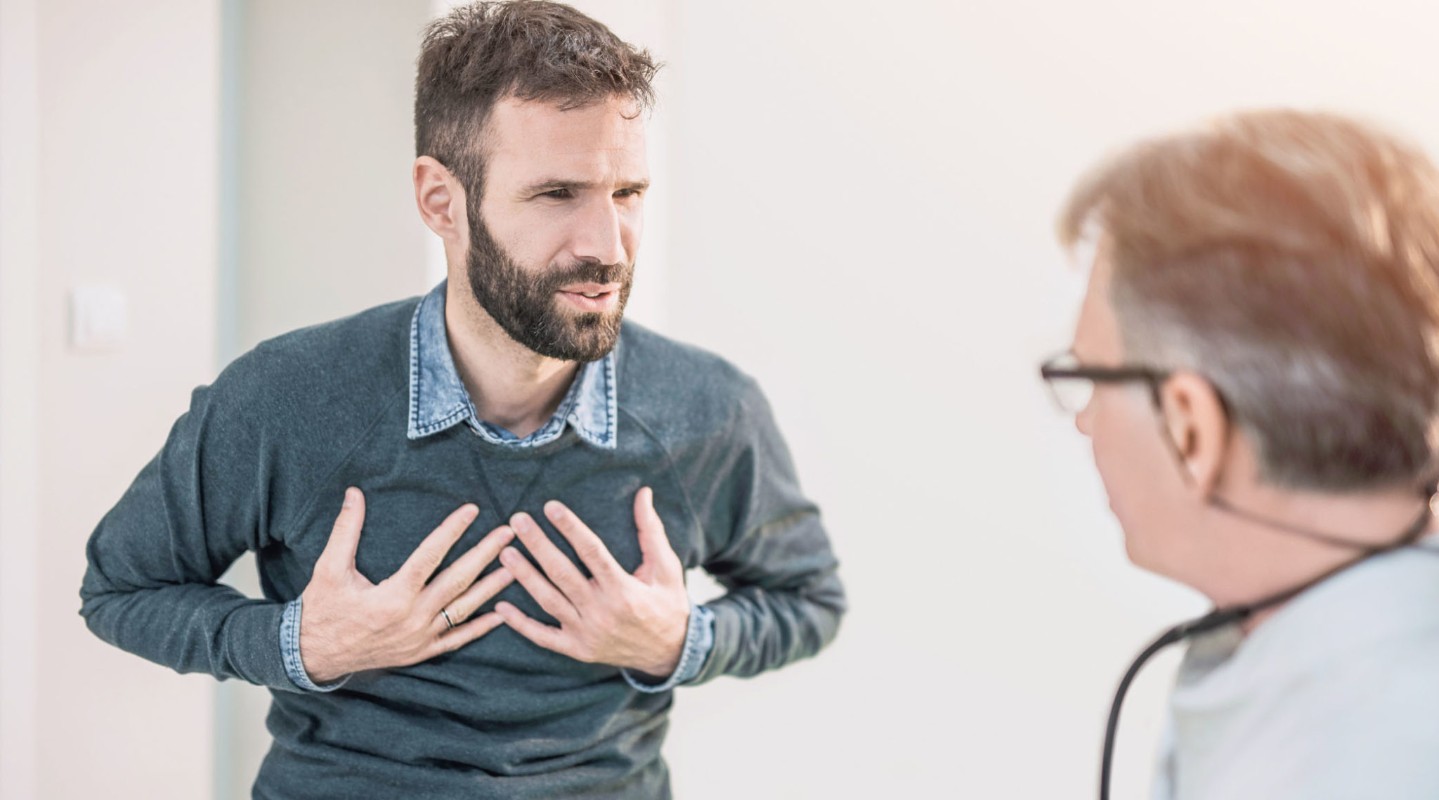 Mid adult male patient describing a chest pain to his doctor.