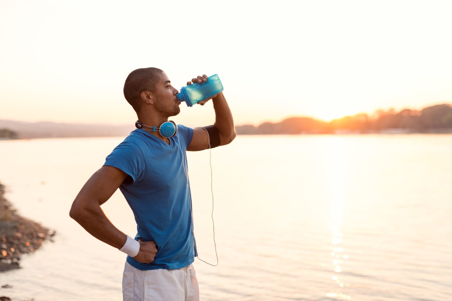 Cropped shot of a young sportsman drinking water while running on riverbank. Warm sunset tones.||Infographic explaining the symptoms of dehydration including thirst, dry mouth, muscle cramps, fast heart rate, fatigue, headache and dizziness