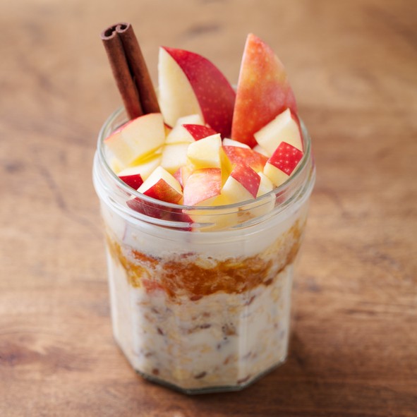 Overnight oats, bircher muesli with apple, cinnamon and honey. Wooden background. Close up.