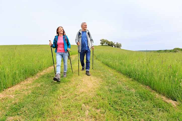 Nordic walking - active mature couple enjoying a green nature walk