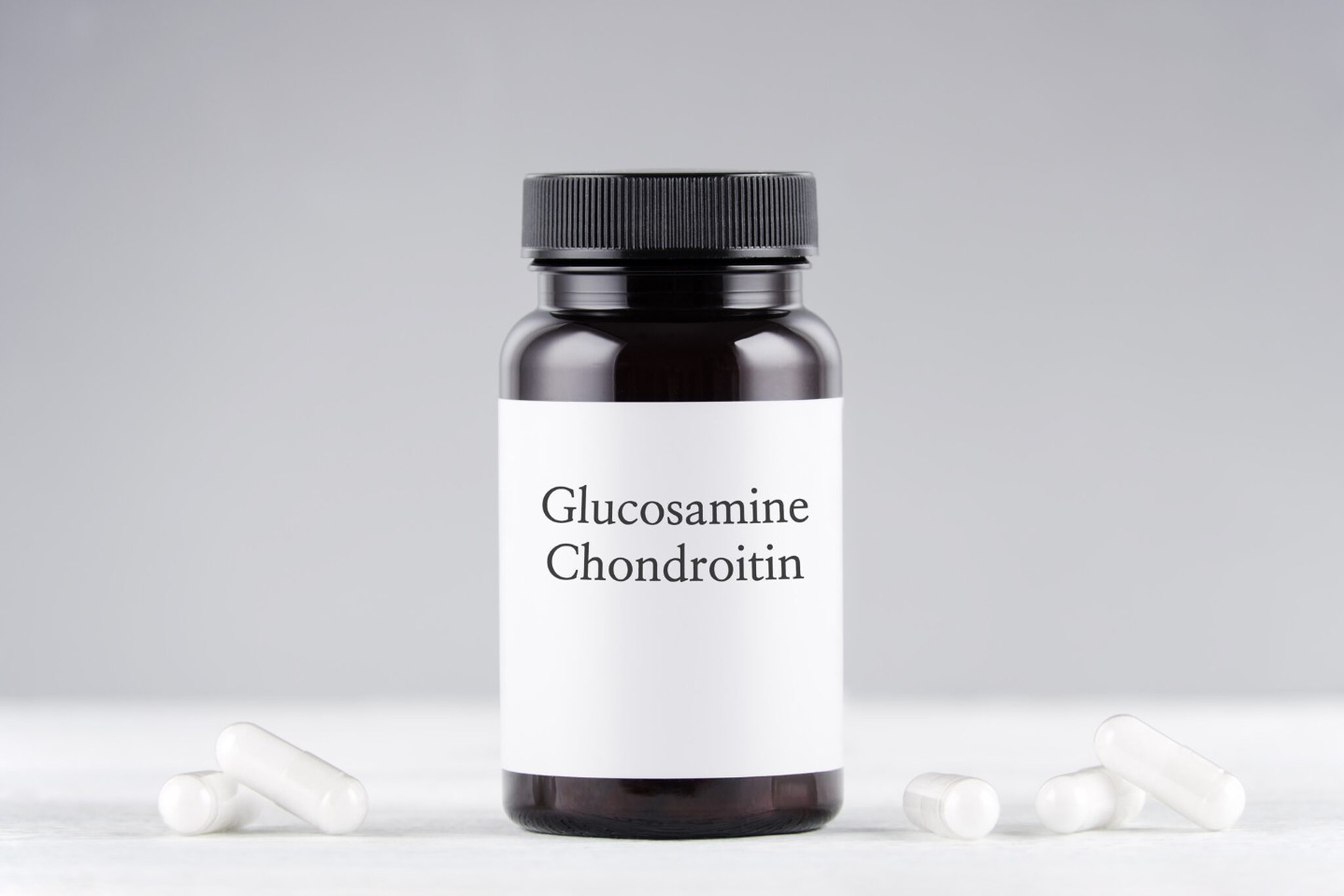 nutritional supplement glucosamine and chondroitin bottle and capsules on gray