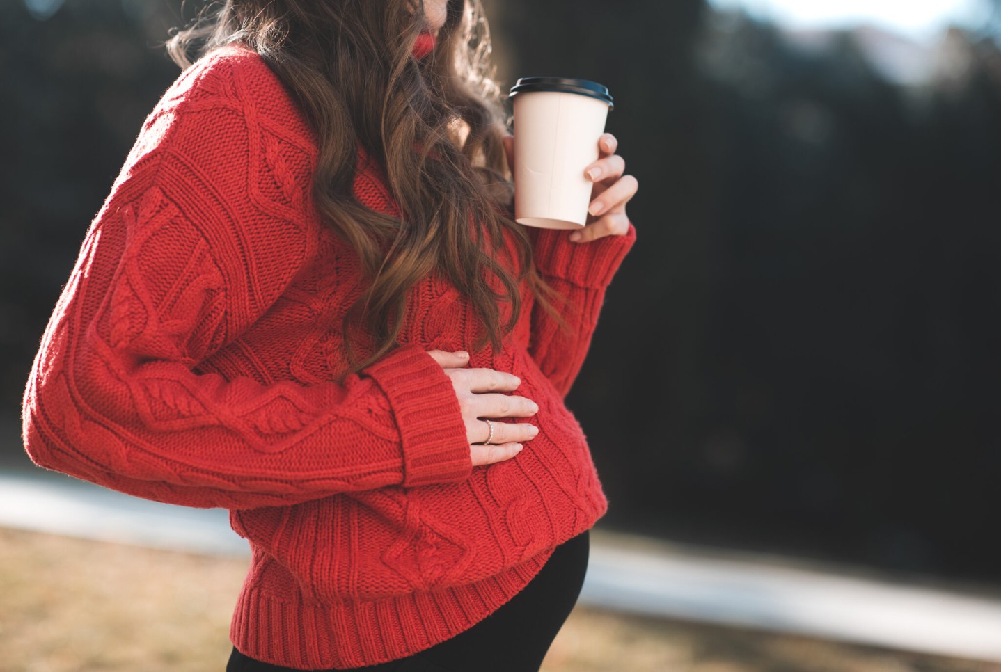 pregnant woman drinking coffee outdoors