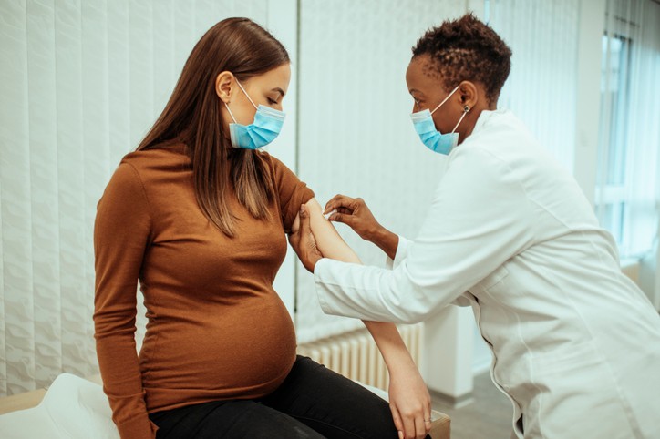 African American female doctor preparing a pregnant woman for vaccination