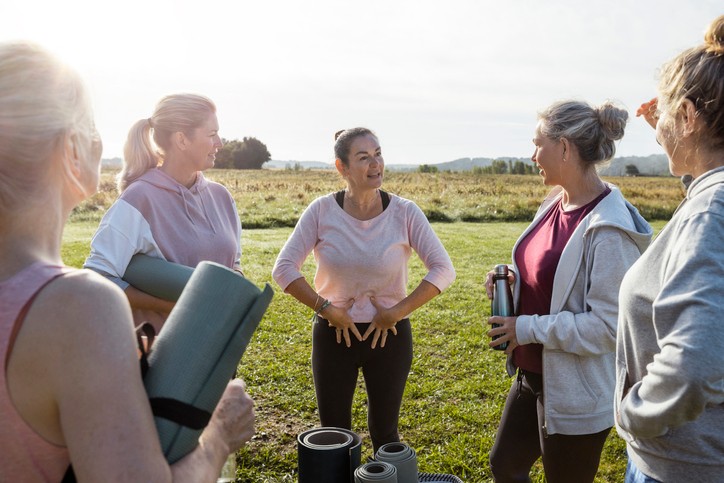 Group of mature women doing Yoga outdoors in France together while on a wellness vacation. They are all standing holding their mats ready to get started. The yoga instructor is giving advice on the exercises they will be doing.||Young happy woman having non-invasive treatment for urinary incontinence at the clinic.