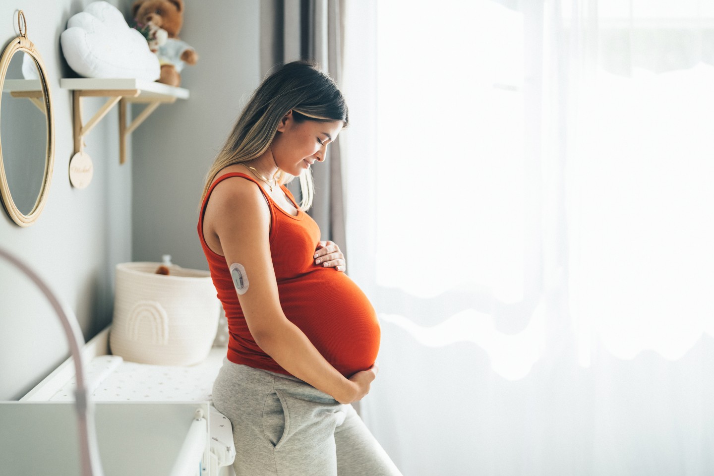 Pregnant woman standing in a white nursery 