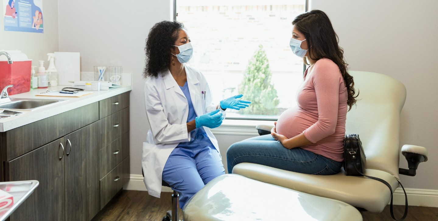 Pregnant woman talking to doctor in clinic