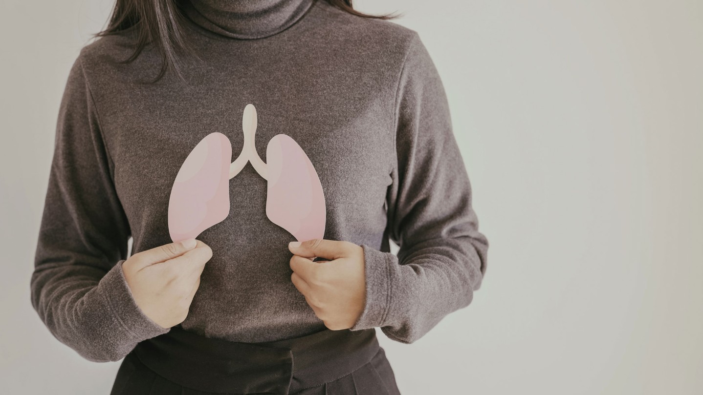 Woman holding up paper cutout of lungs
