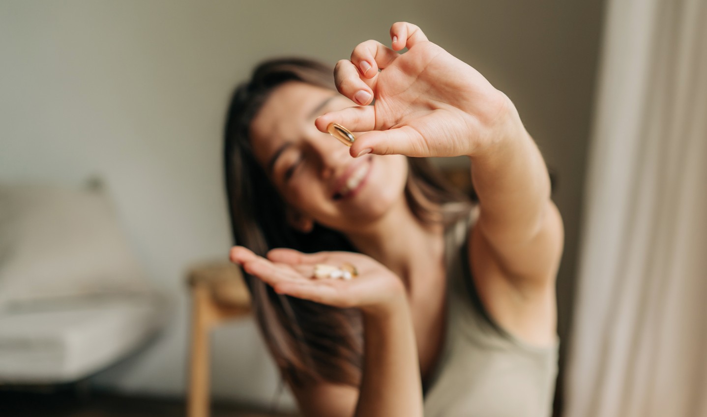 Smiling woman holding a vitamin