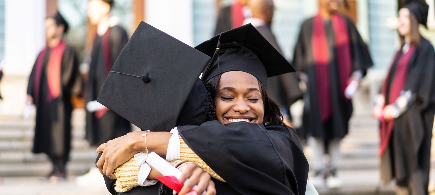 Two women hugging in graduation gowns